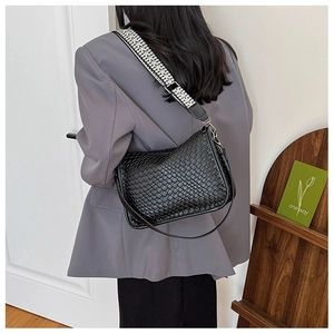 Detail of woven black hobo bag featuring a stylish geometric patterned wide strap