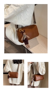 Detail of brown litchi leather cylinder bag with vintage wide strap and rabbit charm