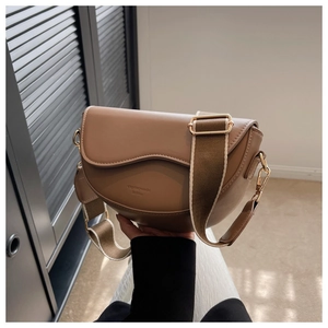 Close-up of camel saddle bag with wide fabric strap and gold hardware details