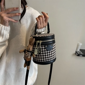 Classic houndstooth bucket bag with rabbit charm and adjustable black shoulder strap