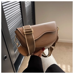 Detail of a brown leather saddle bag with adjustable wide strap and gold hardware