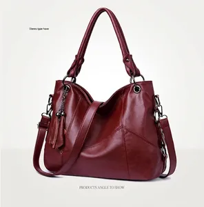 Vue latérale du sac à main en cuir PU bordeaux avec coutures et pompon décoratif