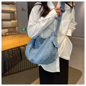 Detail view of large denim messenger bag with multiple pockets and wide shoulder strap