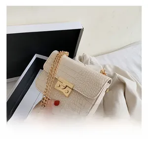Detailed shot of crocodile embossed beige bag with golden chain and metal clasp