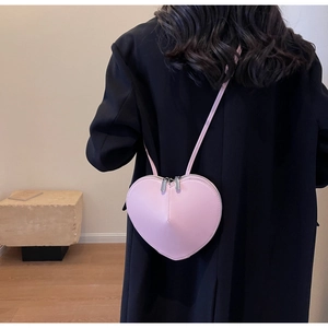 Vista posteriore della modella con borsa a tracolla rosa a forma di cuore e zip argentate