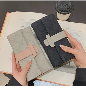 Détails de portefeuilles longs à fleurs gaufrées avec boucles contrastées sur une table