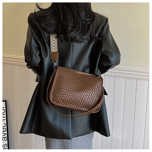 Detailed texture of brown woven leather shoulder bag with ethnic geometric strap