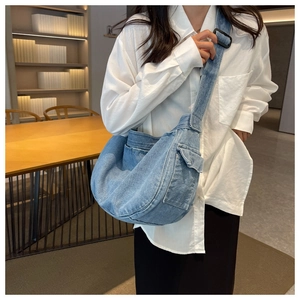 Detailed shot of a light blue denim hobo bag featuring cargo pocket and wide strap