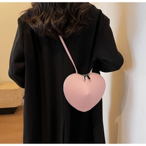 Vue arrière du mannequin portant le sac bandoulière rose en forme de cœur avec zips argentés