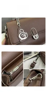 Detailansicht der dunkelbraunen Handtasche mit silbernem Schwan-Anhänger und Beschlägen