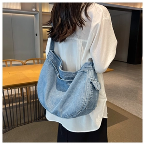 Detailed side view of washed denim messenger bag featuring functional side pocket and retro style
