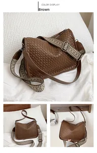 Detail of a brown woven texture shoulder bag with a vintage patterned wide strap