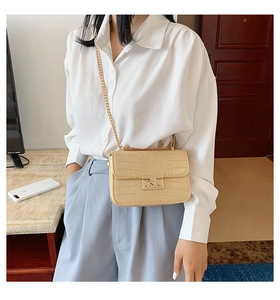 Model showing a beige crocodile embossed crossbody bag with gold chain and square lock