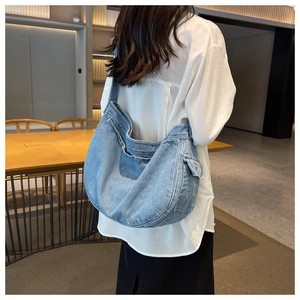 Detail view of light blue denim hobo bag with adjustable strap on a female model
