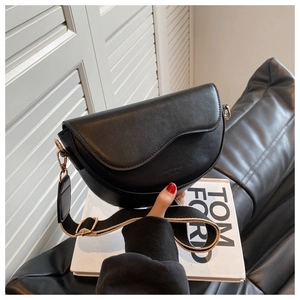 Detail of black matte leather saddle bag with adjustable woven strap and gold hardware