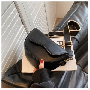 Detail of black semi-circle saddle bag with textured leather and wide fabric strap