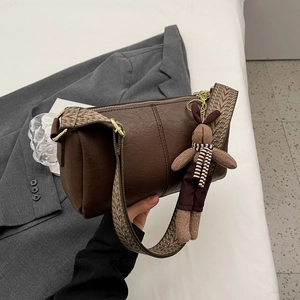 Sac cylindrique marron vintage avec bandoulière tissée et pendentif lapin sur veste