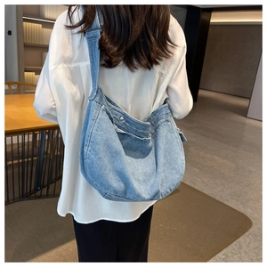 Detail of light blue denim hobo bag showing soft draping and stylish wide shoulder strap