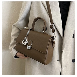 Detail der dunkelbraunen Handtasche aus Leder mit Schwanenanhänger und Drehverschluss