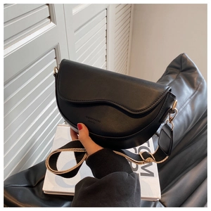 Detail of black semi-circle saddle bag featuring wavy lid and wide fabric strap