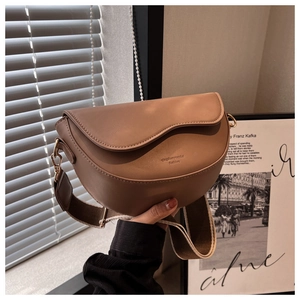 Detailed close-up of textured leather saddle bag with wavy flap and adjustable strap