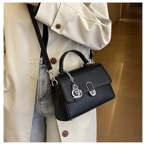 Detailaufnahme einer schwarzen Lederhandtasche mit Drehverschluss und Schwanen-Anhänger