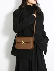 Detail view of brown matte leather crossbody bag with refined golden metal buckle closure
