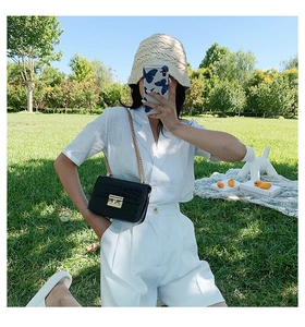 Outdoor shot of a black crocodile pattern crossbody bag with gold chain strap