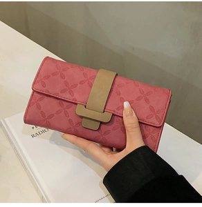 Détails de la texture trèfle embossée et boucle beige sur le long portefeuille rose