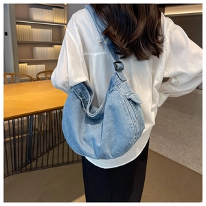 Detail of light blue denim hobo bag with adjustable strap and side pocket in cozy setting