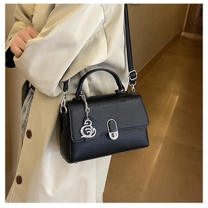 Detail einer schwarzen Handtasche aus Leder mit Silberbeschlägen und Schwanenanhänger