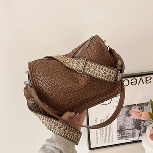 Brown woven shoulder bag with ethnic embroidery strap in a minimalist setting