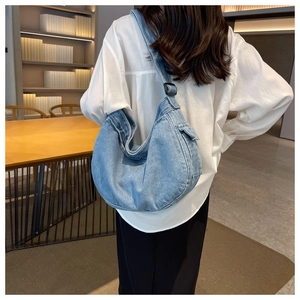 Adjustable denim hobo bag in light blue shown from a back-worn model perspective