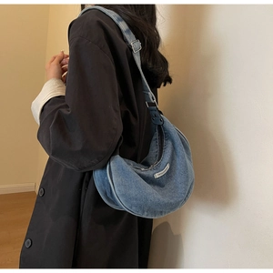 Macro view of blue denim hobo bag featuring silver hardware and fashion label