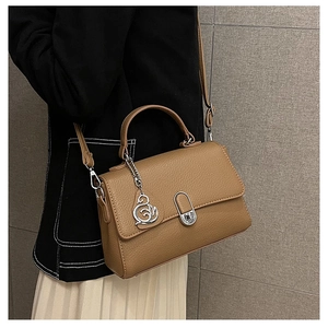 Nahaufnahme der khakifarbenen Ledertasche mit Schwanenanhänger und Metallverschluss