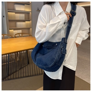Detail view of denim messenger bag with adjustable wide strap and side pocket design
