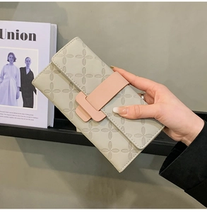 Gros plan d'un long portefeuille à fleurs avec boucle rose H tenu par une main