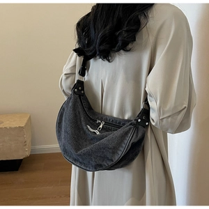 Close-up of gray washed denim crossbody bag with adjustable strap and rivet details