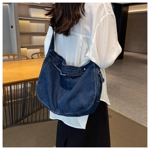 Detail view of large denim hobo bag featuring dark blue fabric and contrast stitching