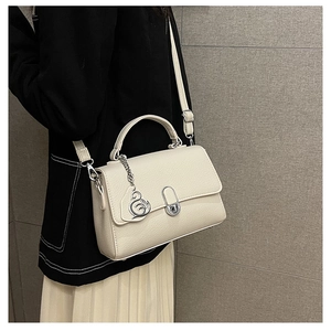 Detail der cremefarbenen Handtasche aus Leder mit elegantem Schwan-Anhänger