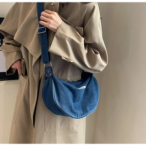 Sac croissant en denim bleu avec étiquette de mode et bandoulière sur un trench