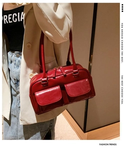 Detail of red glossy leather handbag with double front pockets and shoulder strap