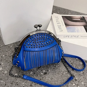 Kleinblaue PU-Lederhandtasche mit Metallfransen und Punk-Nieten auf grauem Boden