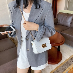 White croc-effect crossbody bag with gold chain strap shown in a modern interior setting
