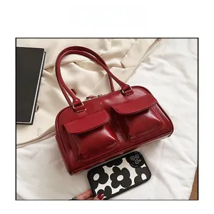 Detail view of red glossy leather handbag with double front flap pockets and dual handles