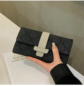 Détail du portefeuille long noir à motif trèfle et boucle contrastée grise