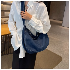 Detail of dark blue denim hobo bag featuring contrast white stitching and metal buckle