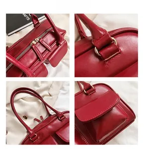 Detail view of dark red leather handbag showing dual zippers and premium golden hardware