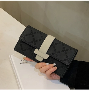 Détail de portefeuille en cuir noir à fleurs embossées avec fermeture à boucle en T grise