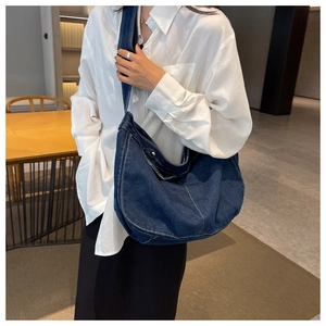 Detailed view of blue denim crossbody bag with contrast stitching and metal snap button